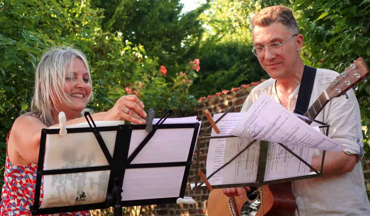 Une chanteuse à clarinette à gauche et un guitariste chanteur à droite